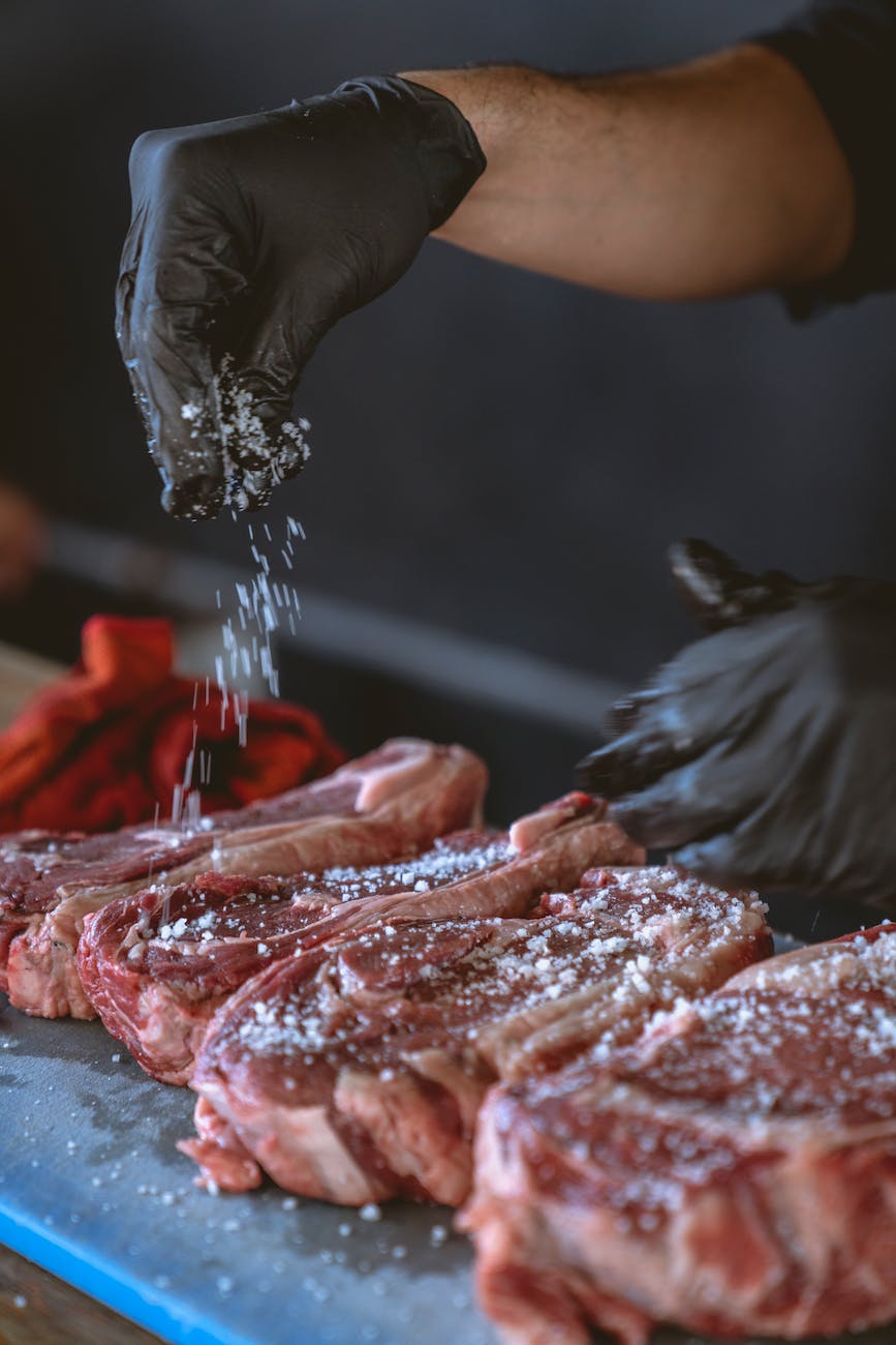 person seasoning the steak